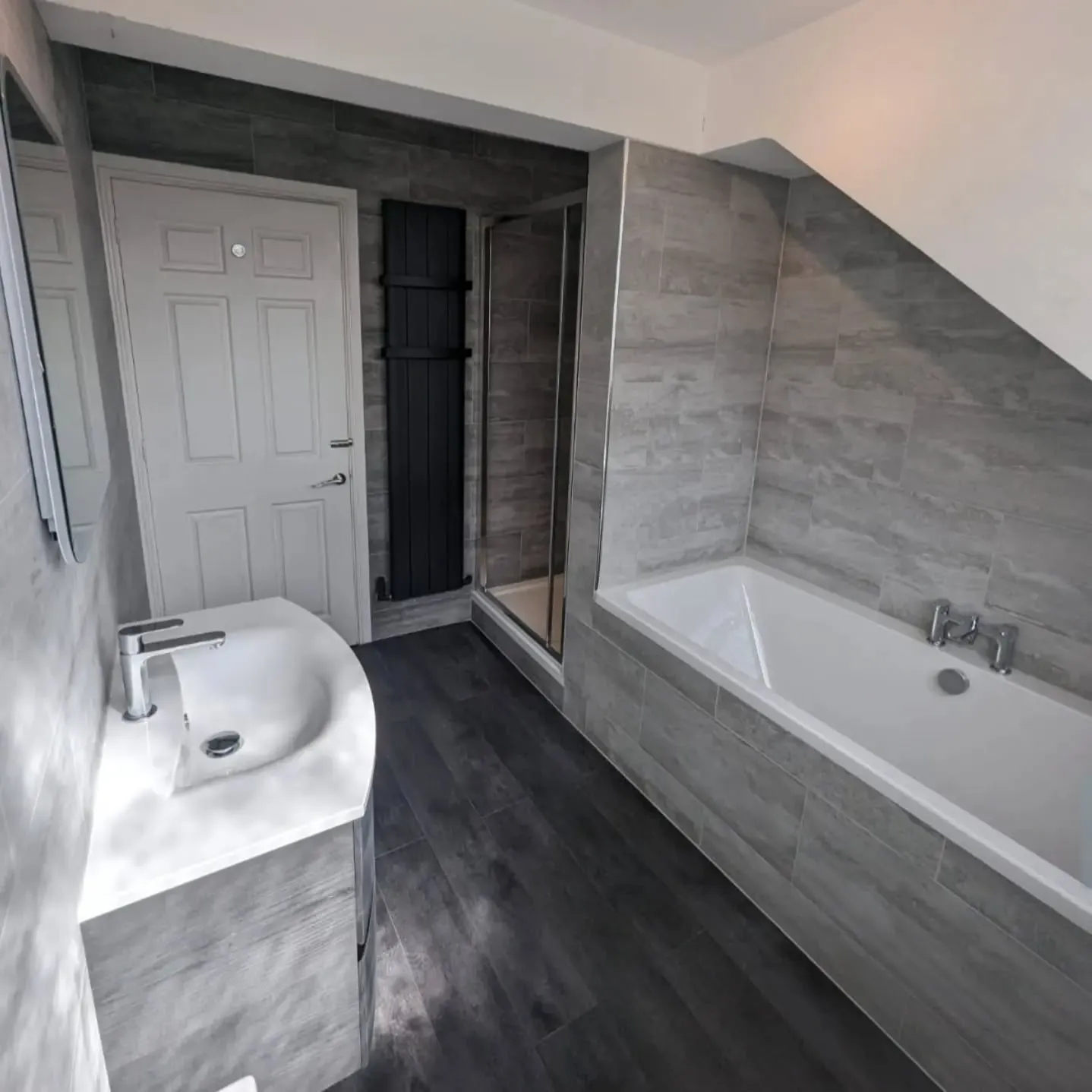 A bathroom with a bath, sink, and mirror.