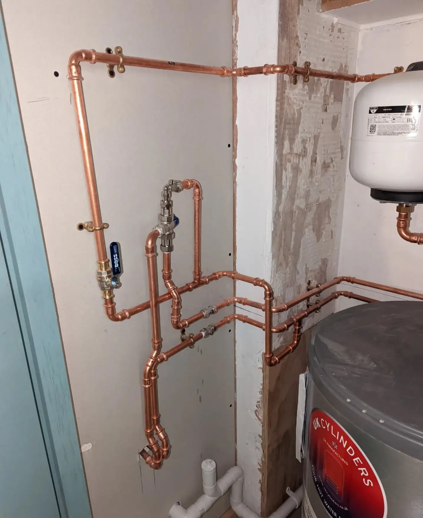 A water heater and pipes in a bathroom.