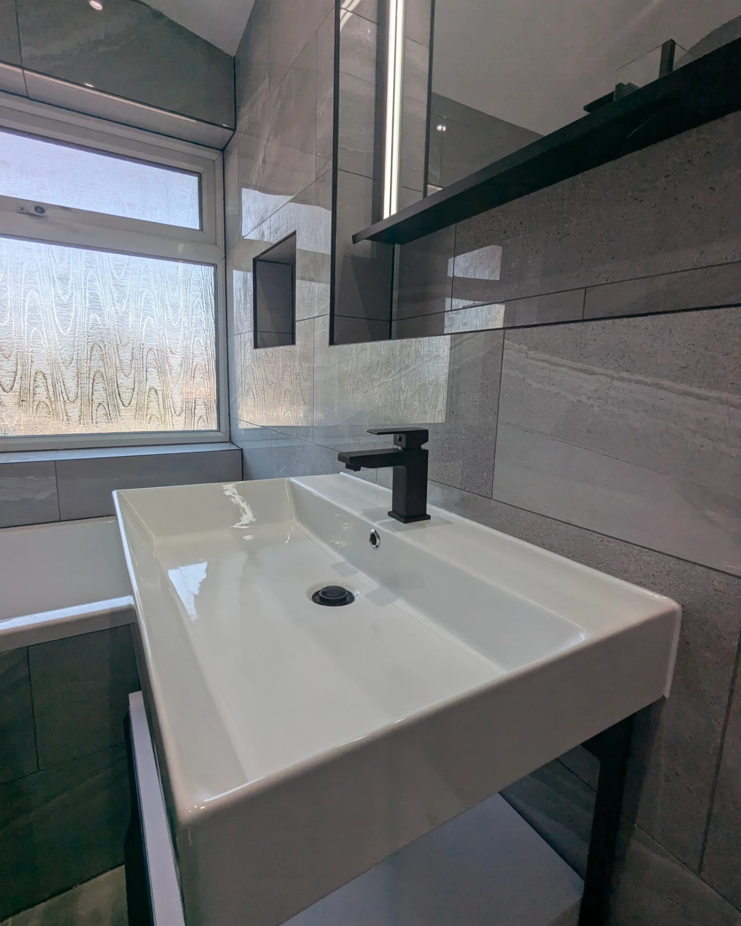 A white sink sitting under a bathroom mirror.